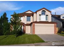 Charming two-story home featuring a well-manicured lawn, brick accents, and an attached two-car garage at 1406 Vinca Pl, Superior, CO 80027