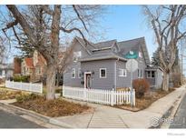 Charming gray home with a white picket fence and landscaped front yard on a sunny day at 211 E Geneseo St, Lafayette, CO 80026