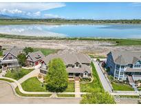 Stunning aerial view of home with lake views, mature trees, landscaping, and inviting front porch at 3916 Fowler Ln, Longmont, CO 80503