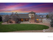 Stunning home with a manicured lawn and mountain views under a colorful sunset sky at 8023 Dawnhill Cir, Erie, CO 80516