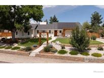 Charming single story home featuring a landscaped front yard and solar panels on the roof at 14117 W 58Th Pl, Arvada, CO 80004