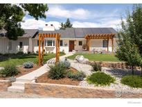 Charming ranch-style home with a manicured front yard, solar panels, and inviting wood pergolas at 14117 W 58Th Pl, Arvada, CO 80004