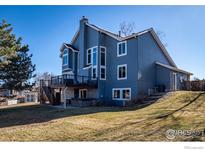 Side view of a two-story blue house with a deck, a chimney, and a hot tub on a sunny day at 1625 Adobe Pl, Highlands Ranch, CO 80126