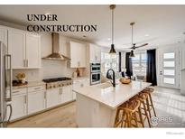 Bright kitchen featuring white cabinets, stainless steel appliances, and an island with bar seating at 2759 Bear Springs Cir, Longmont, CO 80503