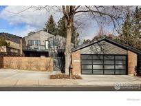 Contemporary home featuring a gray exterior with brick accents, a glass garage door, and well-kept landscaping at 3865 Newport Ln, Boulder, CO 80304