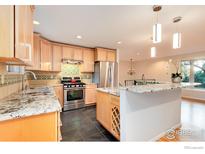 Modern kitchen featuring stainless steel appliances, granite countertops, tile backsplash, and light wood cabinetry at 4652 Hampshire St, Boulder, CO 80301