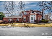 Charming two-story brick home featuring a manicured lawn and inviting front entrance with a bay window at 664 Manorwood Ln, Louisville, CO 80027