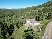 Beautiful home exterior surrounded by lush greenery and mountain views under a clear blue sky at 67 S Peak Rd, Boulder, CO 80302