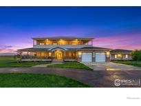 Inviting two-story home featuring a wraparound porch, two-car garage, and well-manicured lawn at sunset at 1255 Mill Creek Rd, Berthoud, CO 80513