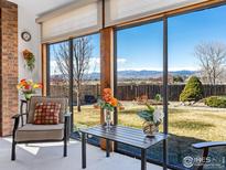 Bright sun room with chairs, table, brick wall, and large windows providing a view of the outdoor space and landscape at 161 Baylor Dr, Longmont, CO 80503