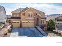 Charming two-story home with a well-manicured front yard, a three-car garage, and a beautiful brick entrance at 18740 W 85Th Dr, Arvada, CO 80007