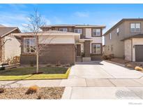 Charming two-story home showcasing a well-maintained lawn, brick accents, and a spacious driveway on a sunny day at 18926 W 93Rd Ave, Arvada, CO 80007