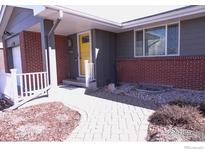 Charming front entrance featuring a brick facade, yellow door, and well-maintained landscaping at 2996 S Lamar St, Denver, CO 80227