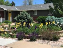 Charming home featuring colorful flower beds, mature trees, and a well-maintained lawn at 2996 S Lamar St, Denver, CO 80227