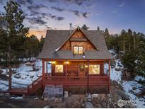 Charming wood home with a covered porch, nestled in a snowy mountain setting at dusk at 439 Ronnie Rd, Golden, CO 80403