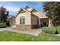 Inviting single-story home with manicured lawn, stone accents and neutral siding at 836 Windflower Dr, Longmont, CO 80504