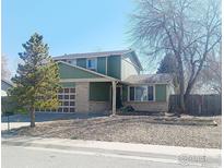 Charming two-story home with an attached garage and a well-maintained front yard and blue skies above at 9852 W 76Th Ave, Arvada, CO 80005