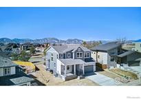 Beautiful two-story home features a gray exterior, landscaped yard, and mountain views in the background at 1039 Willow Pl, Louisville, CO 80027