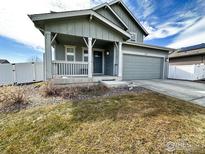 Charming single-Gathering home featuring a covered front porch, two-car garage, and well-maintained lawn at 1495 Biffle Ct, Berthoud, CO 80513