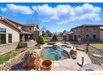 Luxurious backyard with a custom rock water feature, stone patio, and outdoor seating area, perfect for entertaining at 1652 Poplar Ave, Boulder, CO 80304