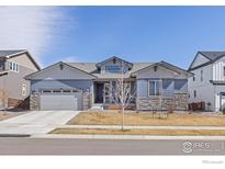 Charming single-story home with a two-car garage, gray siding, and stone accents on a sunny day at 420 Orion Cir, Erie, CO 80516