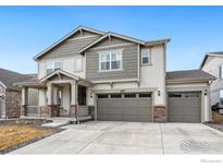 Charming two-story home with neutral siding, stone accents, covered porch, and a three-car garage at 4940 Preserve Pl, Firestone, CO 80504