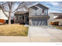 Charming two-story home with gray siding, brick accents, and a well-maintained front lawn at 5411 E 128Th Dr, Thornton, CO 80241