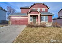 Charming two-story home with a red exterior, complemented by a well-manicured lawn and a two-car garage at 6140 Ralston St, Frederick, CO 80530