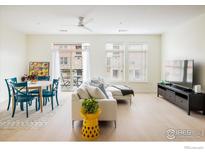 Bright living room featuring a comfortable white sofa, dining area, and a balcony with natural light at 13456 Via Varra # 119, Broomfield, CO 80020