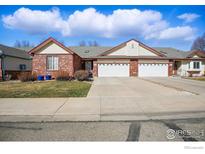 Traditional brick townhome featuring a two-car garage and neutral-toned exterior at 1602 Oak Ridge Ln, Longmont, CO 80501