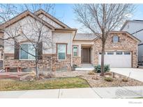 Charming home featuring stone accents, neutral stucco, a two car garage, and a well maintained lawn at 1614 Hideaway Ct, Longmont, CO 80503