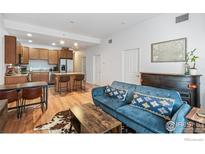 Open-concept living room featuring hardwood floors, a modern kitchen, and stylish furnishings at 1950 N Logan St # 502, Denver, CO 80203