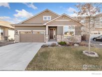 Charming home featuring a manicured lawn and a two-car garage with stone accents at 2342 Spotswood St, Longmont, CO 80504