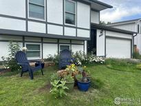 Charming exterior featuring lawn with flowers and two chairs on the front lawn, attached garage, and two-story design at 339 S Hoover Ave, Louisville, CO 80027