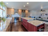 Bright kitchen features stainless appliances, tile backsplash, and a red island with granite countertop at 339 S Hoover Ave, Louisville, CO 80027