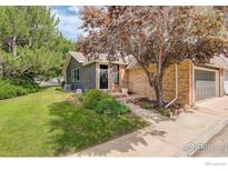 Charming home exterior features mature trees, a lush lawn and attached two-car garage at 4996 Clubhouse Cir, Boulder, CO 80301