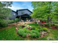 Landscaped backyard with stone retaining wall, built-in grill, outdoor seating area, and mature trees at 835 Linden Ave, Boulder, CO 80304