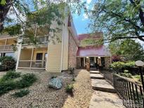 Condo building with balconies, brick accents, red roof, and front walkway framed by mature trees and low-maintenance landscaping at 14760 E Kentucky Dr # 312, Aurora, CO 80012