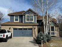 Charming two-story home featuring a brick and blue siding exterior, complemented by a well-manicured front yard and driveway at 1618 Garnet St, Broomfield, CO 80020