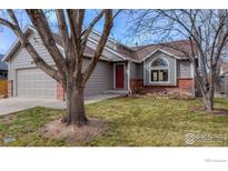 Charming home featuring a well-manicured lawn, red front door, and an attached two-car garage at 1624 Foster Dr, Longmont, CO 80501