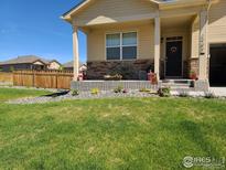 Charming single-Gathering home featuring a welcoming front porch, lush lawn, and well-maintained landscaping at 1799 Jade Ave, Brighton, CO 80603