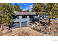 Charming exterior view showcasing gray siding, a two-car garage and mature trees at 191 Alder Ln, Boulder, CO 80304