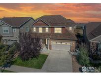 Beautiful two-story home with a well-manicured lawn and a two-car garage, set against a vibrant sunset backdrop at 2310 Provenance St, Longmont, CO 80504