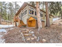 Charming home exterior featuring a deck, shed, and natural stone steps at 30690 Highway 72, Golden, CO 80403