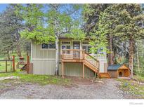 Charming exterior of cabin with wooden porch and dog house in forested setting at 30690 Highway 72, Golden, CO 80403