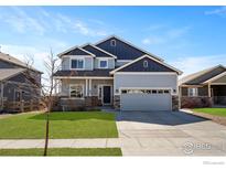 Charming two-story home with a well-manicured lawn, a covered porch, and a two-car garage at 655 Lene Ln, Berthoud, CO 80513