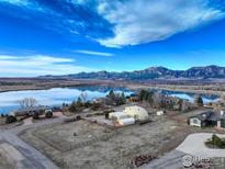 Breathtaking aerial view of a unique home, serene lake, and majestic mountains in the background at 6611 Lakeview Dr, Boulder, CO 80303