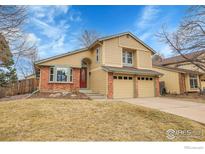 Inviting two-story home with brick accents, attached two-car garage, and manicured front lawn at 10895 W Half Moon Pass, Littleton, CO 80127