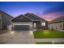 Charming single-story home featuring a well-manicured lawn and attached two-car garage at dusk at 1525 Waterman St, Berthoud, CO 80513