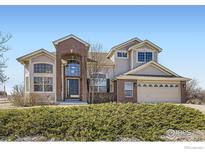 Charming two-story home featuring a brick facade, arched entryway, and well-maintained landscaping at 16021 Verbena St, Brighton, CO 80602